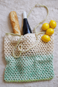 crochet market bag shown holding bread, wine and lemons