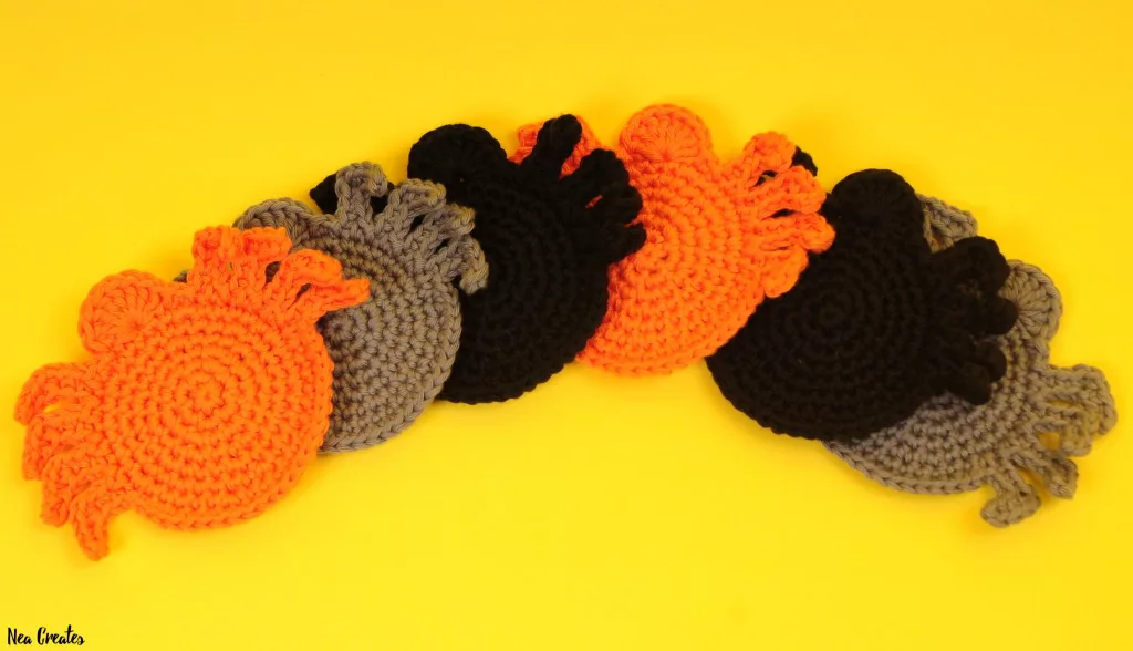 Black crochet spider coaster with a round body, small eyes and eight dimensional legs.