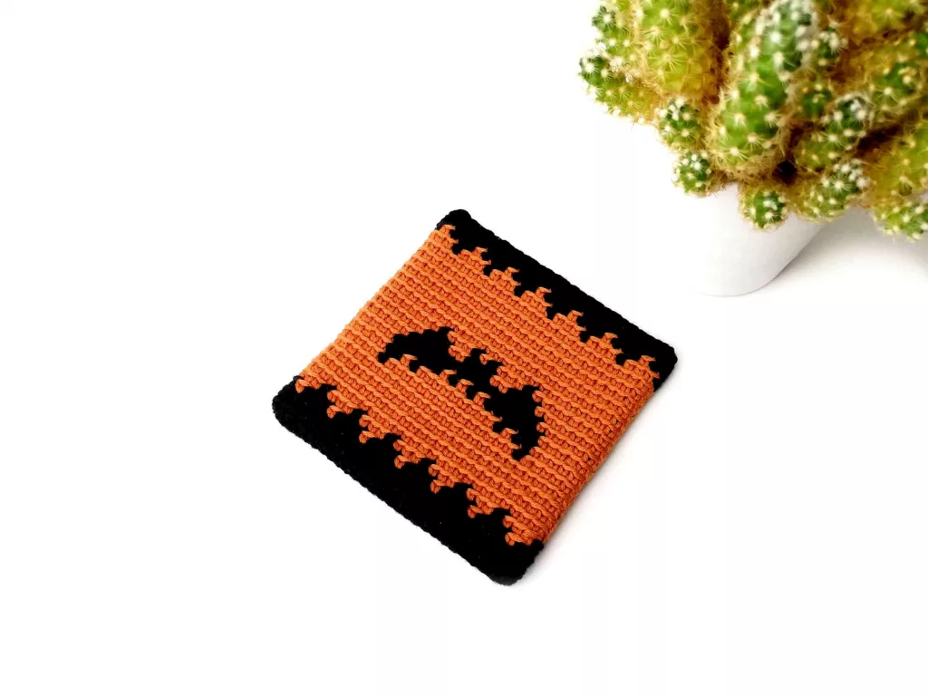Round tapestry crochet Halloween coaster featuring a dark bat silhouette.