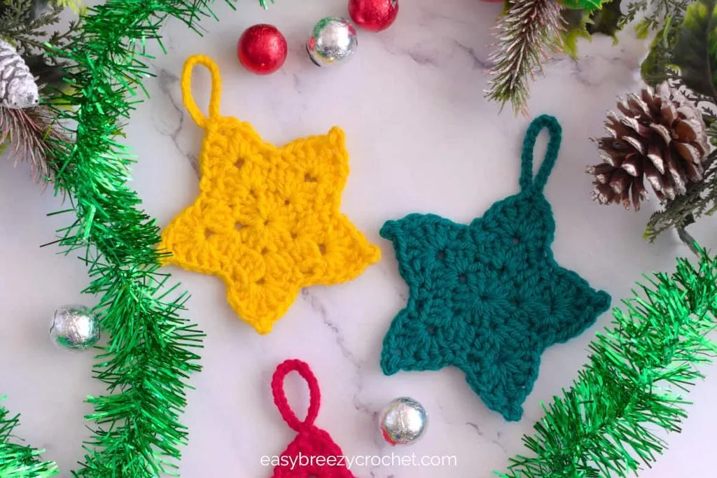 Simple yellow crocheted star ornament hanging from a branch